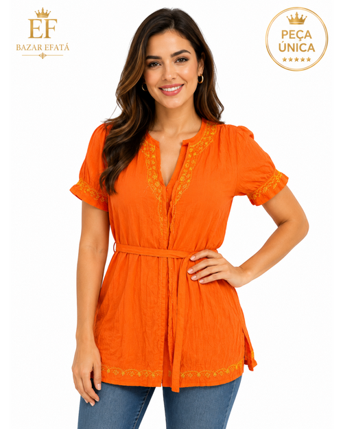 Modelo veste bata laranja BAZAR OFICIAL EFATA com bordados delicados, mangas curtas e faixa ajustável na cintura.