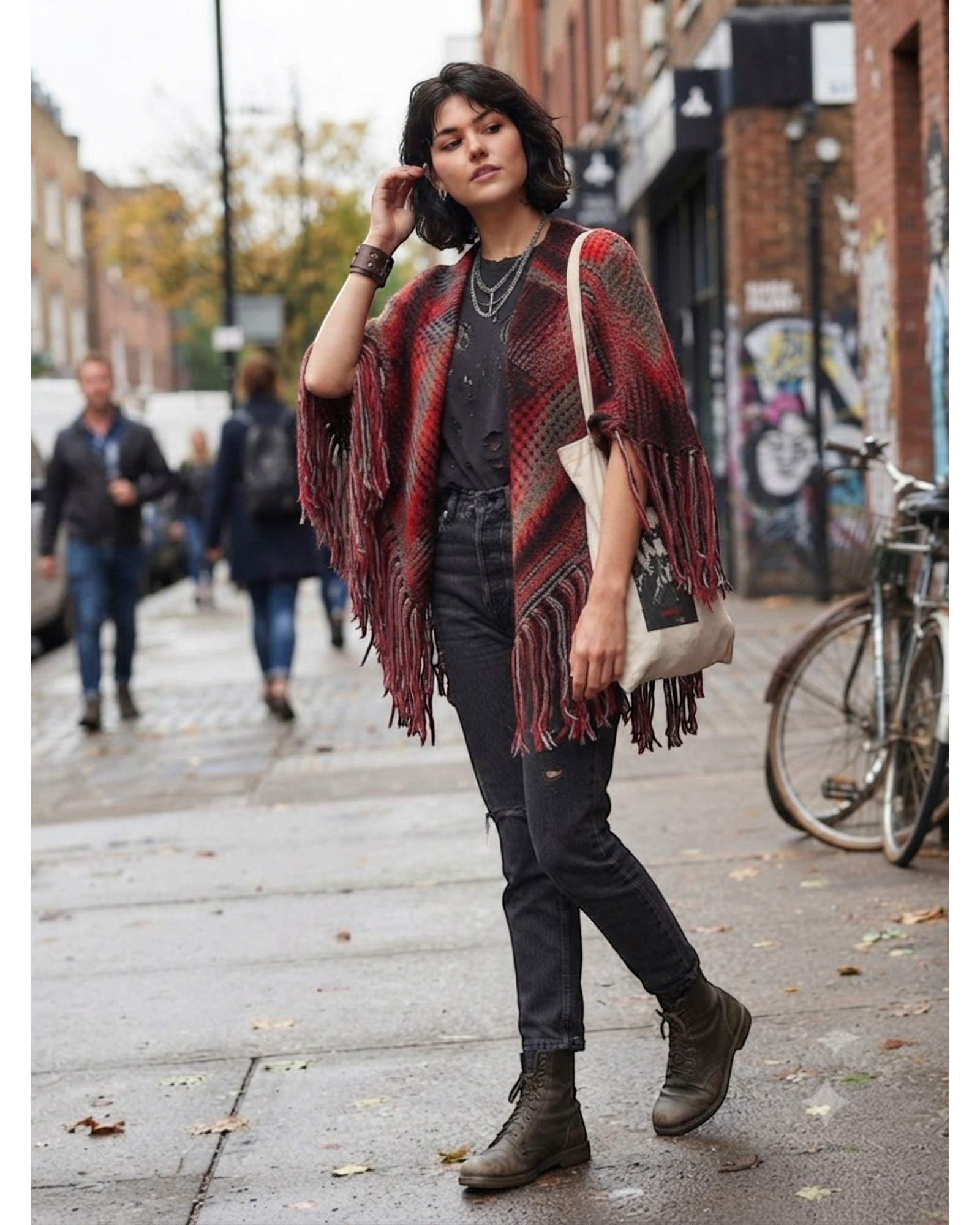 Modelo usando poncho de tricô listrado BAZAR OFICIAL EFATA em tons de vermelho, preto e cinza com franjas boho chic.