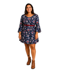 Modelo sorridente vestindo vestido floral azul-marinho com mangas flare e cinto vermelho do BAZAR OFICIAL EFATA